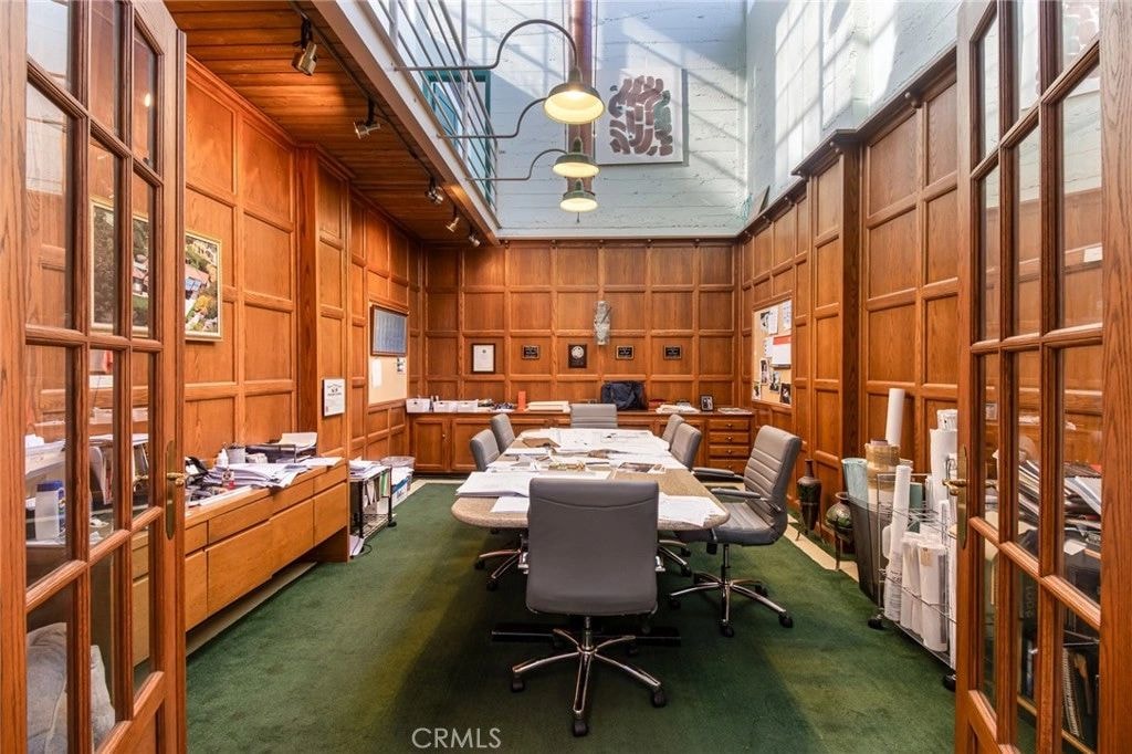 The Oak Room today — a wood-paneled office with an oval conference table, pendant lights, and a skylit high ceiling