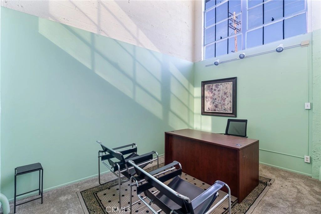 The Heritage Suite space today — a simple office with mint-green walls, an industrial window, and high ceilings